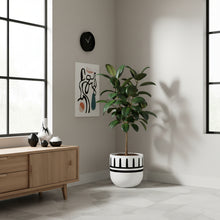 Modern interior with a plant in a decorative pot, wooden cabinet, and abstract art on the wall.