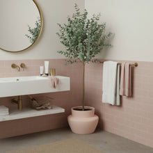 Bathroom interior with pink tiles, a sink, and a potted plant.