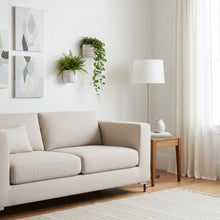 Modern living room with a beige sofa, side table, lamp, and wall art.