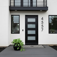Modern house exterior with black door and address numbers '4557'.