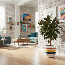 Modern living room with a plant in a colorful pot, brick walls, and artwork.