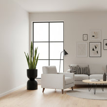 Modern living room with a white armchair, sofa, and decorative elements.