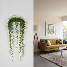Living room with a mustard yellow sofa, decorative pillows, and a hanging plant.