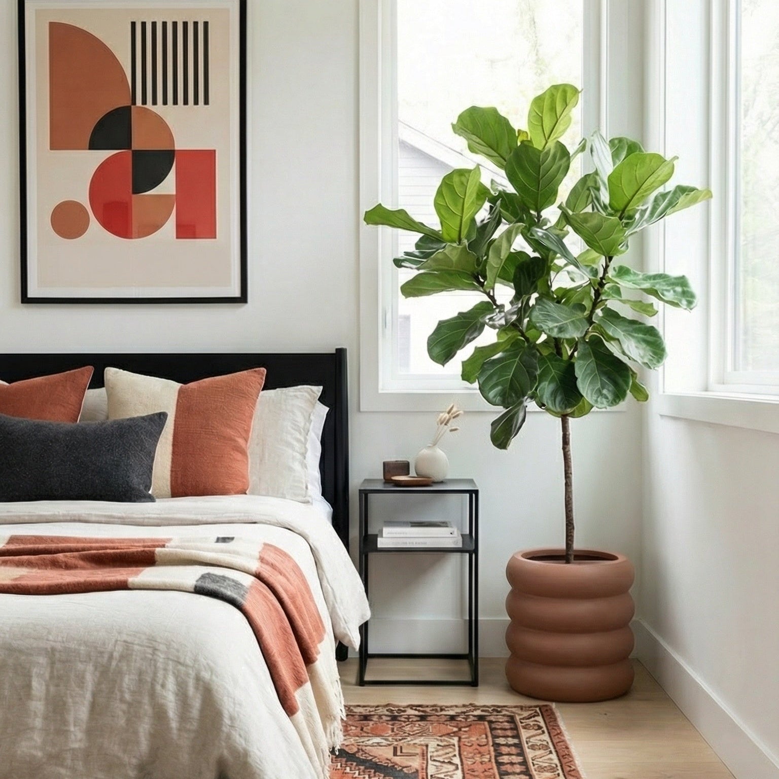Bedroom with a bed, nightstand, and plant near a window.