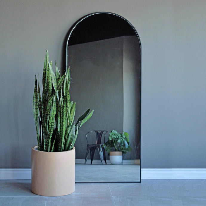 soft pink cylinder placed on floor in front of arched built-in shelving