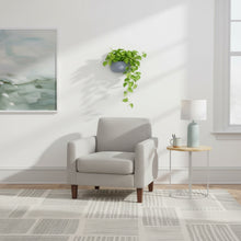 Gray armchair in a modern living room with a plant and side table.