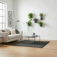 Modern living room with a beige sofa, coffee table, and wall-mounted plants.