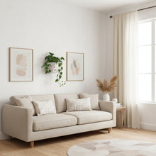 Beige sofa in a living room with neutral decor and natural light.