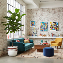 Modern living room with a brick wall, colorful artwork, and a mix of furniture.