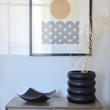 Decorative items on a console table with a framed abstract art piece in the background.
