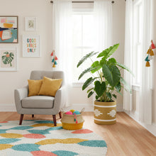 Living room with a gray armchair, colorful rug, and potted plant.