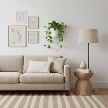 Modern living room with beige sofa, side table, lamp, and wall art.