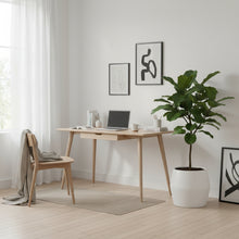 Modern home office with a desk, chair, laptop, and potted plant.