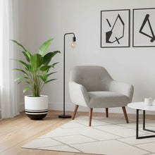 Modern living room with a gray armchair, plant, and coffee table.