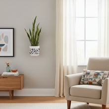 Living room with a beige armchair, wooden side table, and wall plant.
