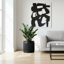 Modern living room with a grey sofa, plant, and abstract black and white painting.