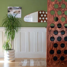 Room interior with a wooden screen, plant, and decorative mirror.