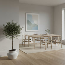 Modern dining room with wooden table and chairs, plant, and abstract art on the wall.