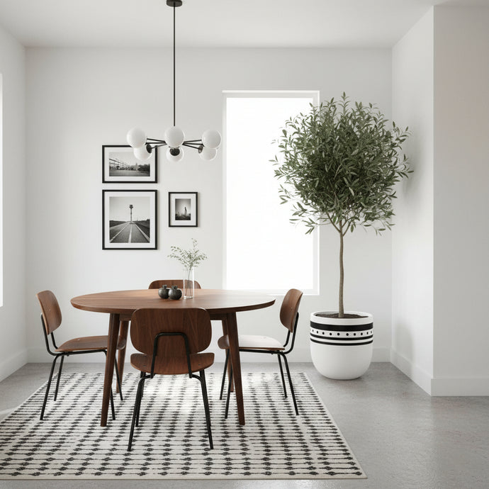 Modern dining room with wooden table and chairs, decorative plant, and framed pictures on the wall.