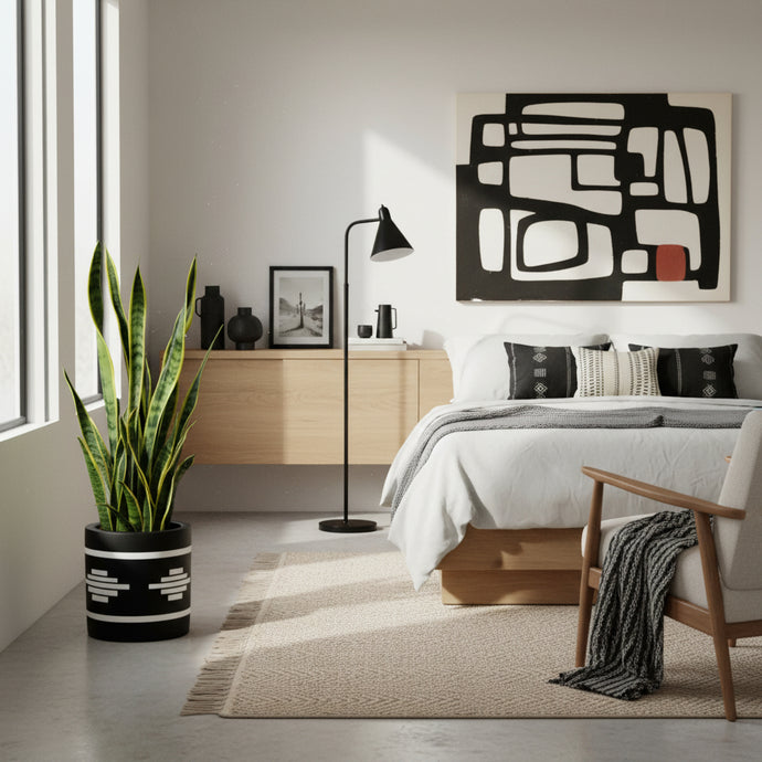 Modern bedroom with a bed, chair, plant, and abstract art on the wall.