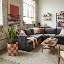 Modern living room with a charcoal sectional sofa, wooden coffee table, and decorative elements.