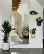hand-painted planters mounted on wall with a mirror reflecting the bed and drum in a modern bedroom