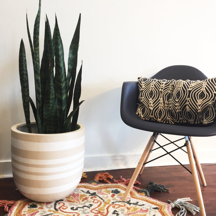 Beige coloured planter with white stripes with a bohemian rug