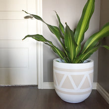 white and light beige planter with triangular design in corner of room