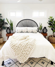 black and white diamond pattern plant pots on beside tables with black rattan headboard