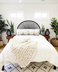 black and white diamond pattern plant pots on beside tables with black rattan headboard