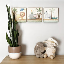 nursery artwork and stuffed animals on dresser with indoor flower pot