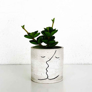 concrete planter pot with an outline of two portraits kissing 