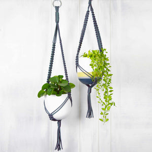 two Common House Studio hand painted planters in grey nylon plant hangers with trailing plants