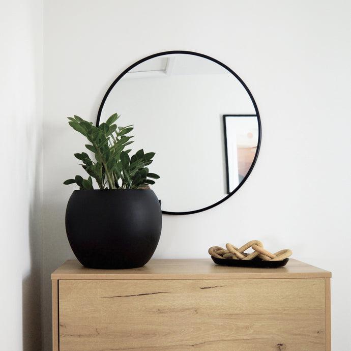 set of large sphere bowl planter placed on floor in corner of home.  Two Serbi rattan and teak wood chairs are placed to the left of a stone mantel.  A tall window lets in a lot of light.