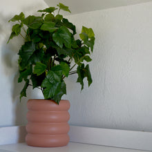 terracotta coloured areaware ring stacked planter pot with fake plant on white counter top.