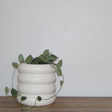 ring stacked tabletop planter pot with trailing plant vines on an oak shelf